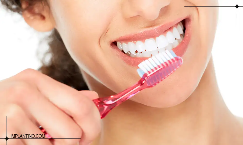 خانمی در حال مسواک زدن و خمیر دندان روی مسواک